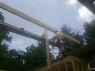 Carpenter setting a ridge beam over a new addition frame — Ice Dam Removal by Roofing Brothers in Largo