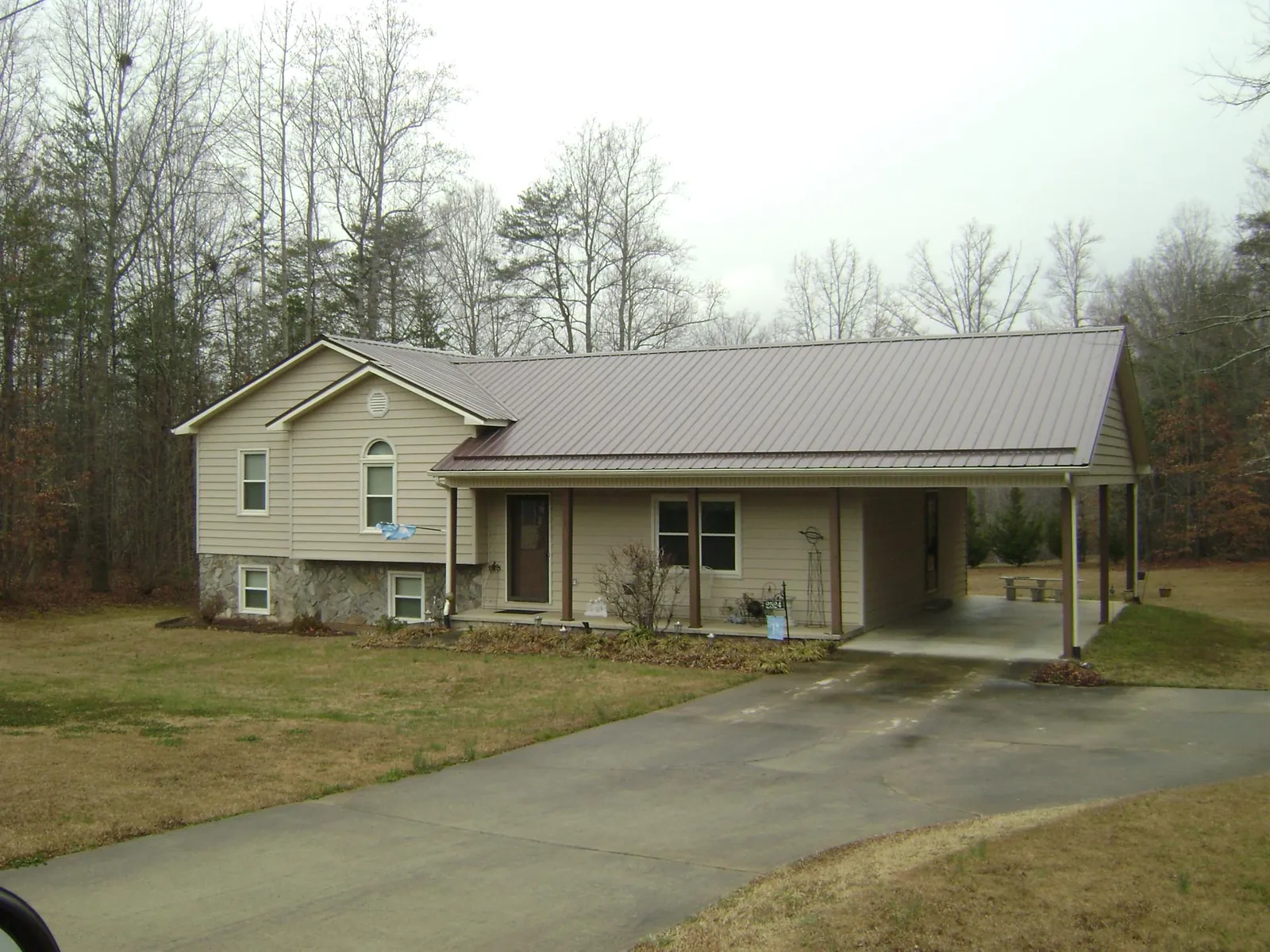 Brown metal roof on a tan split level home with an attached carport in Largo