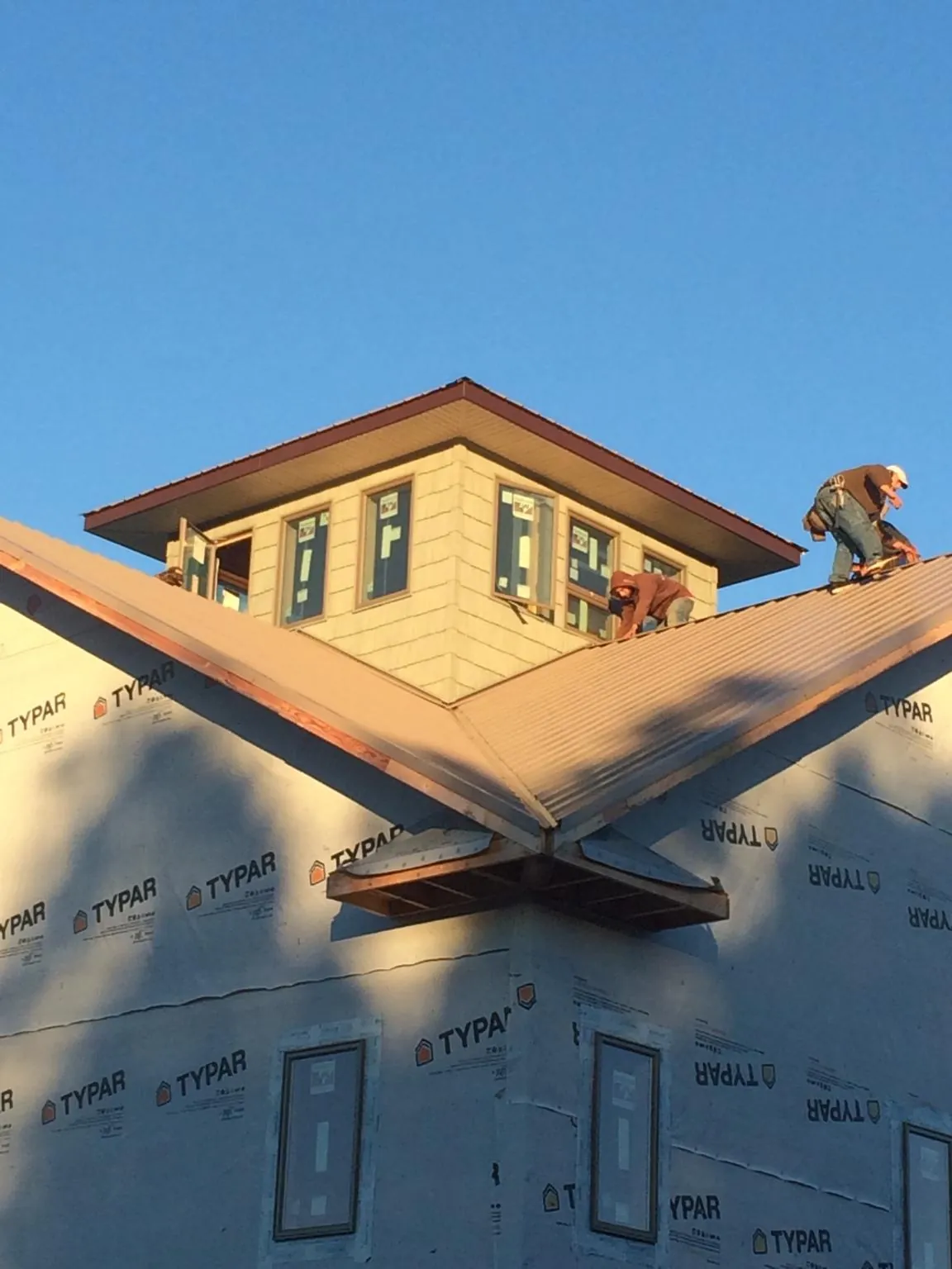 Roofers working around a rooftop cupola on a new metal roof at sunset — Roof Waterproofing in Largo by Roofing Brothers